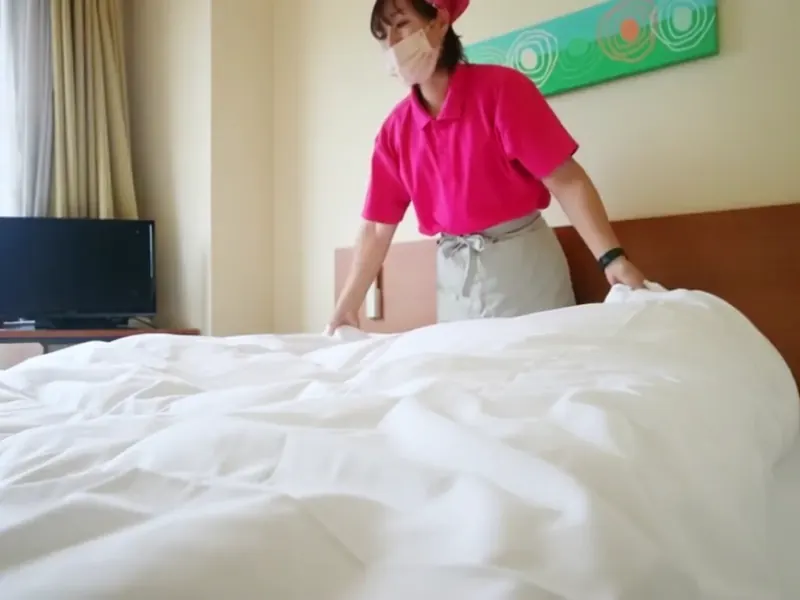 シーツを敷いてベッドを整える様子